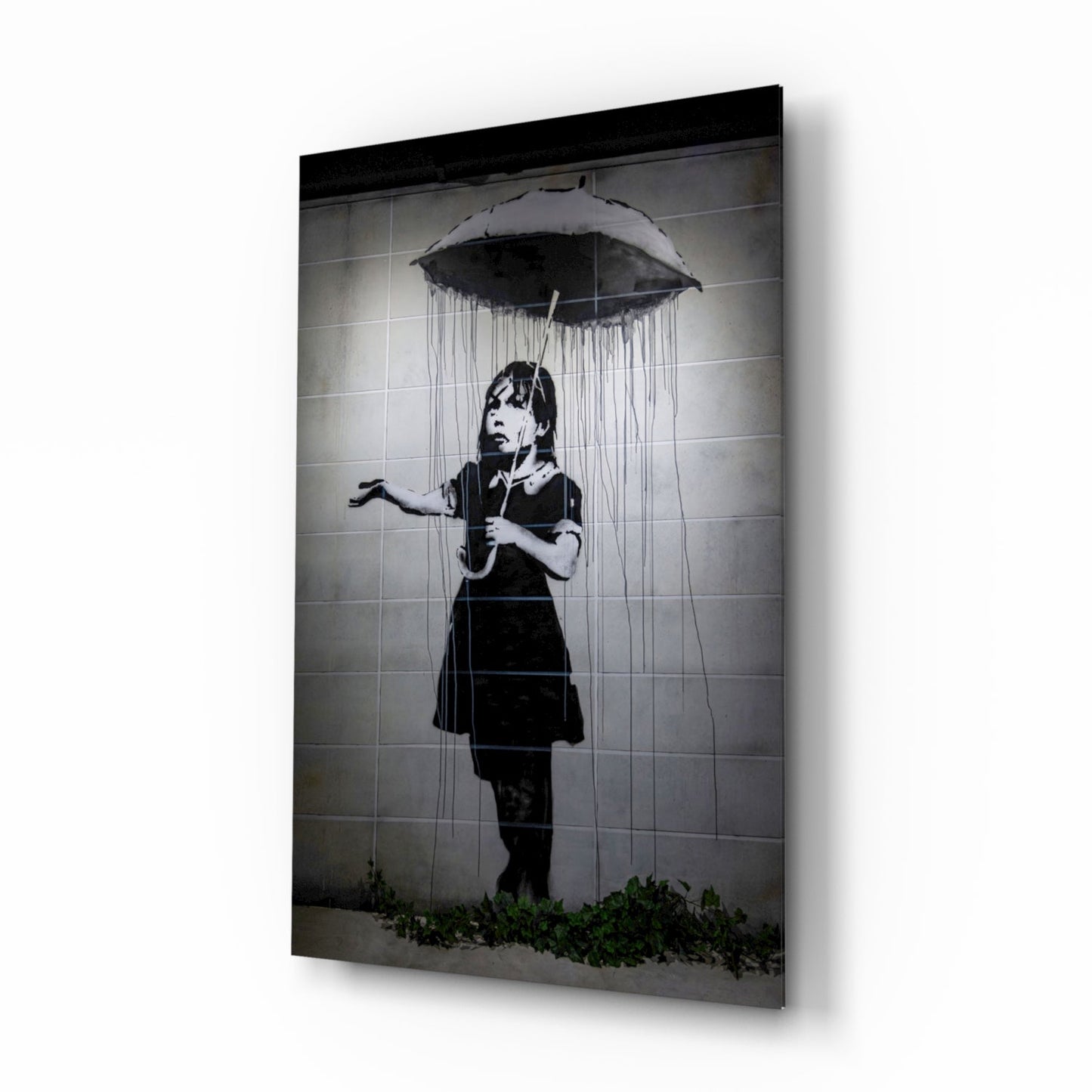 Black and white stencil art on glass panel showing child with umbrella under rain, mounted on white wall.