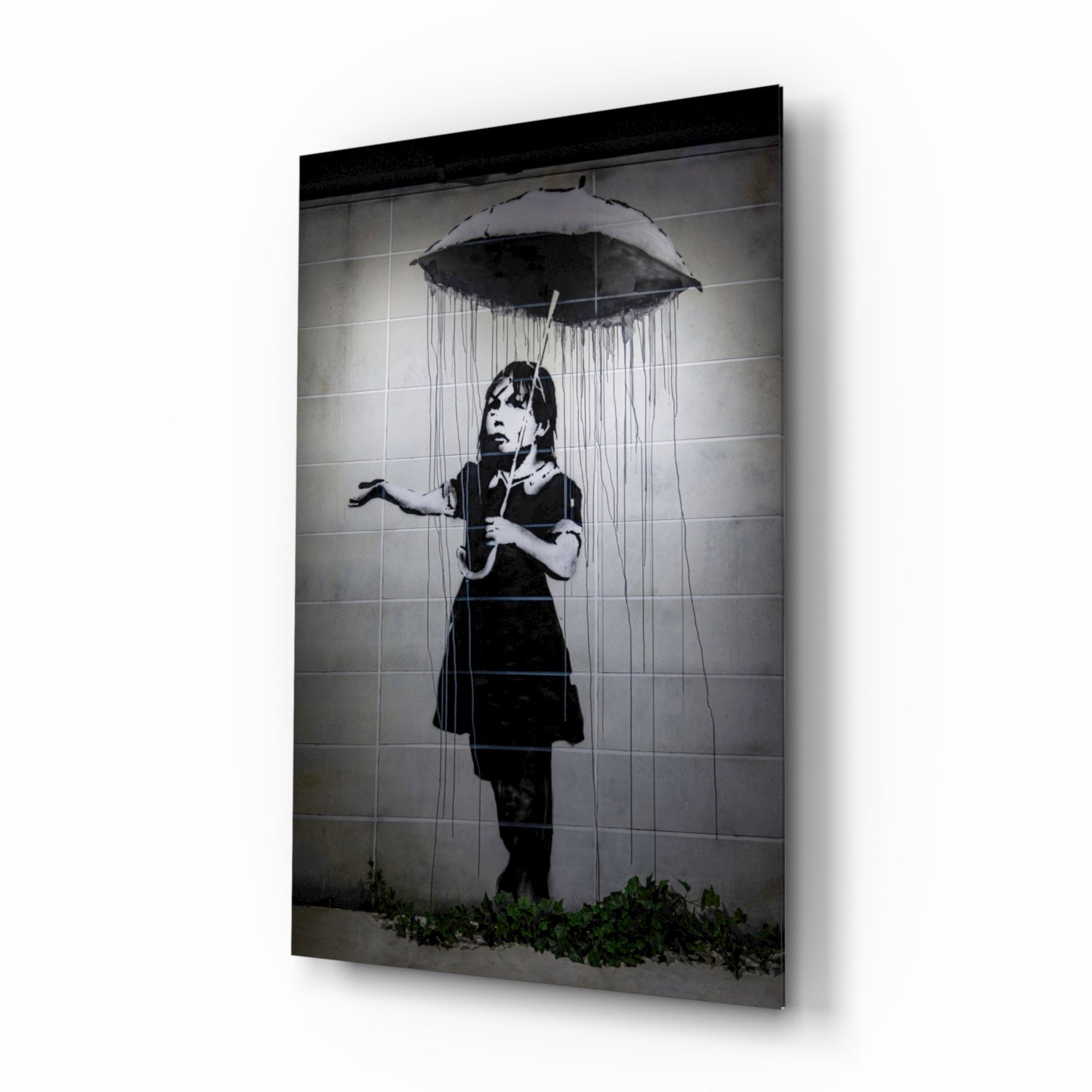 Black and white stencil art on glass panel showing child with umbrella under rain, mounted on white wall.
