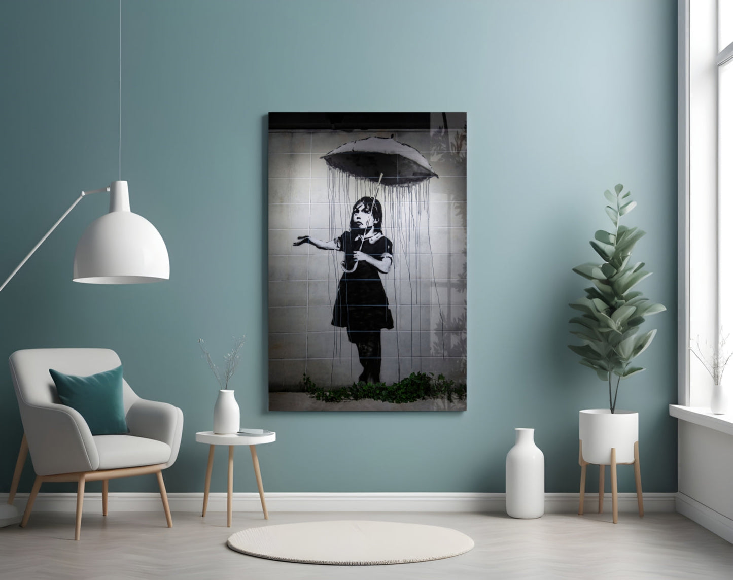 Black and white glass art panel depicting a child holding an umbrella under falling rain, displayed on a teal wall in a minimalist interior setting.