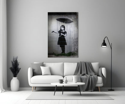 Black and white glass art depicting a child holding an umbrella beneath falling rain, displayed above a white sofa in a minimalist living room.