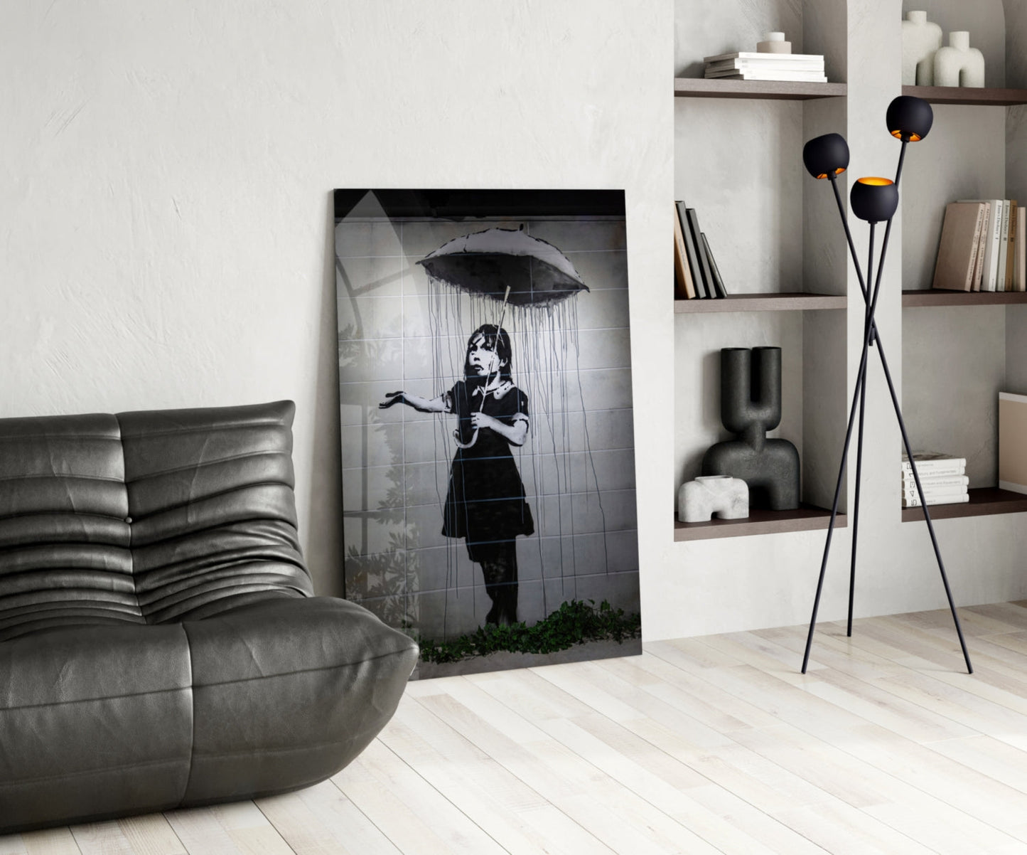 Black and white glass art depicting a child holding an umbrella in rain, displayed in a modern living room with grey furniture and wooden shelving.