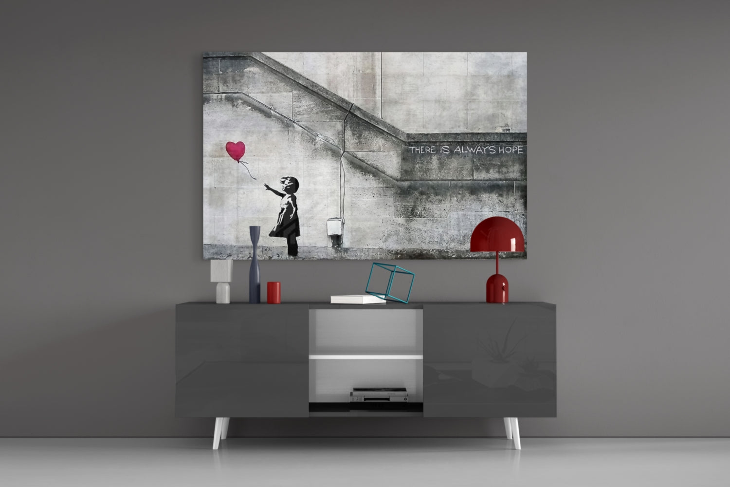 Banksy-style glass art depicting silhouetted girl reaching for red heart balloon displayed above modern media console in minimalist interior.