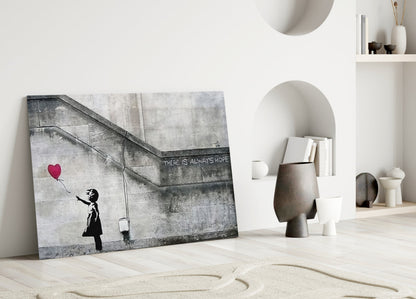 Banksy-style glass art leaning against white wall showing silhouetted girl reaching for red heart balloon with "There Is Always Hope" text.