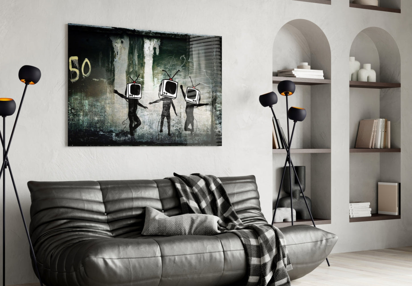 Dark glass art print depicting three stick figures with TV screens for heads against weathered green and gray background, hung above gray leather sofa in modern living room.