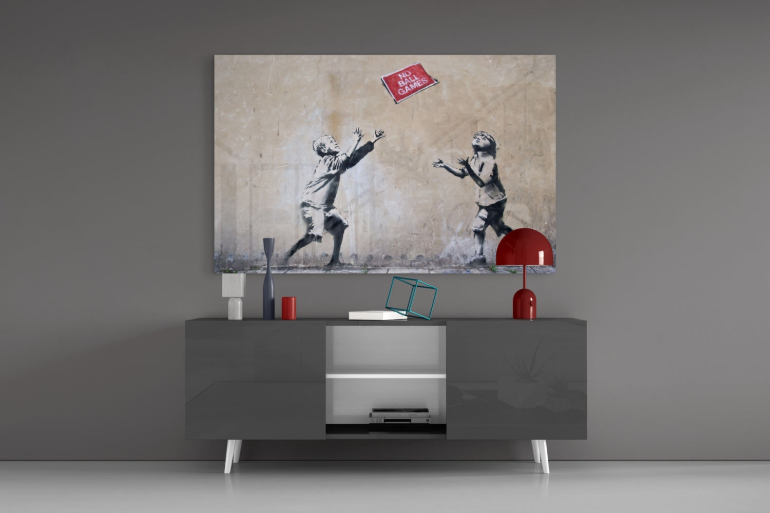 Banksy-style stenciled artwork displayed above gray media console showing two children reaching for red ball, with "NO BALL GAMES" sign visible.