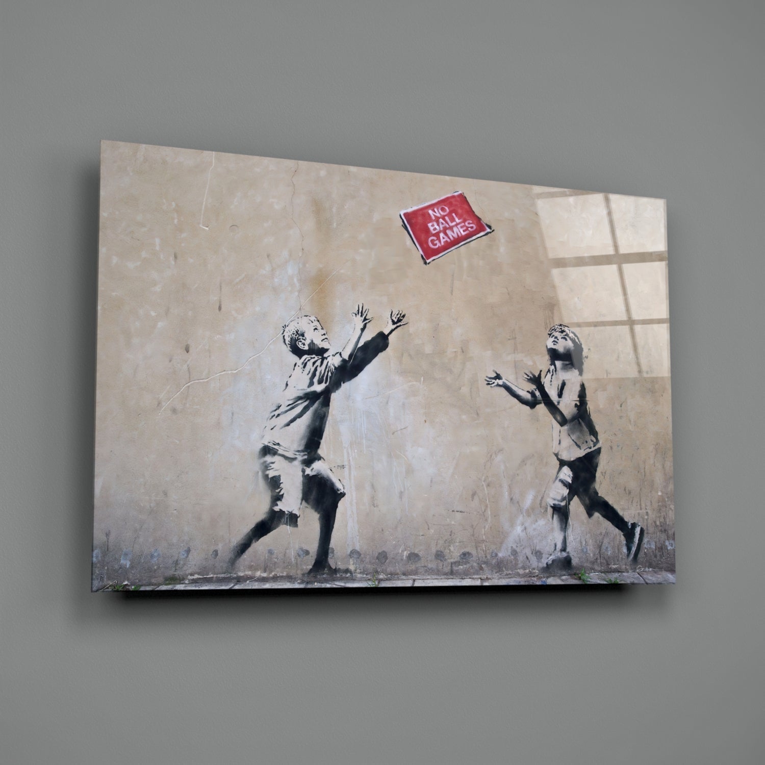 Canvas print of Banksy-style stenciled children reaching for red "No Ball Games" sign on textured beige wall.