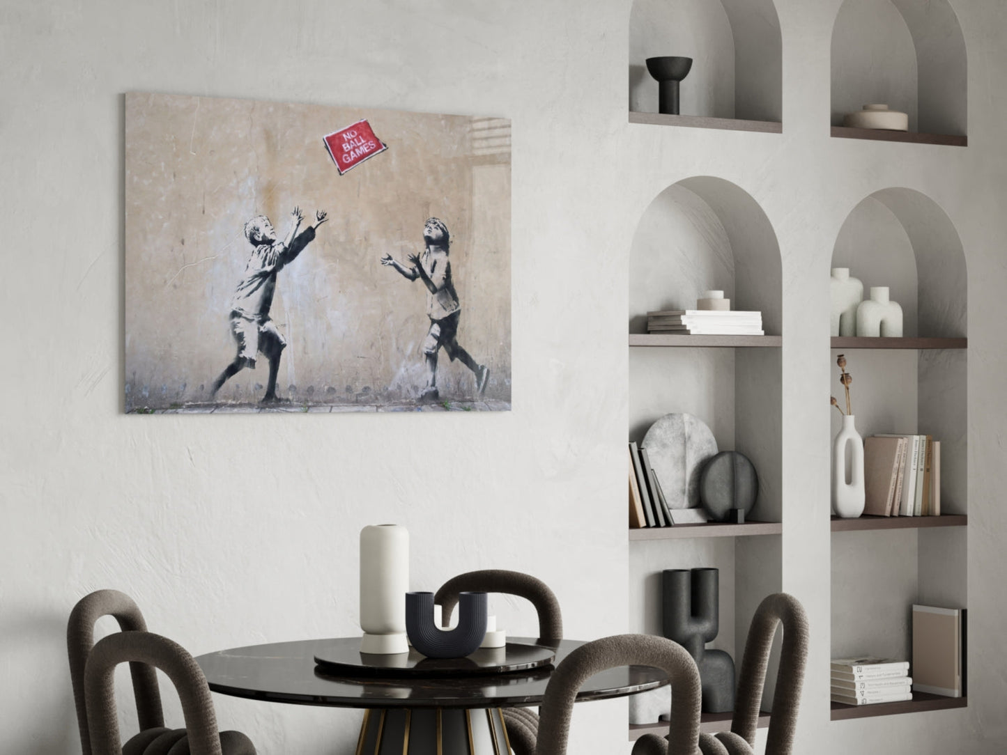 Banksy-style canvas artwork depicting two children reaching for a red "No Ball Games" sign, displayed above a black dining table in a modern interior.