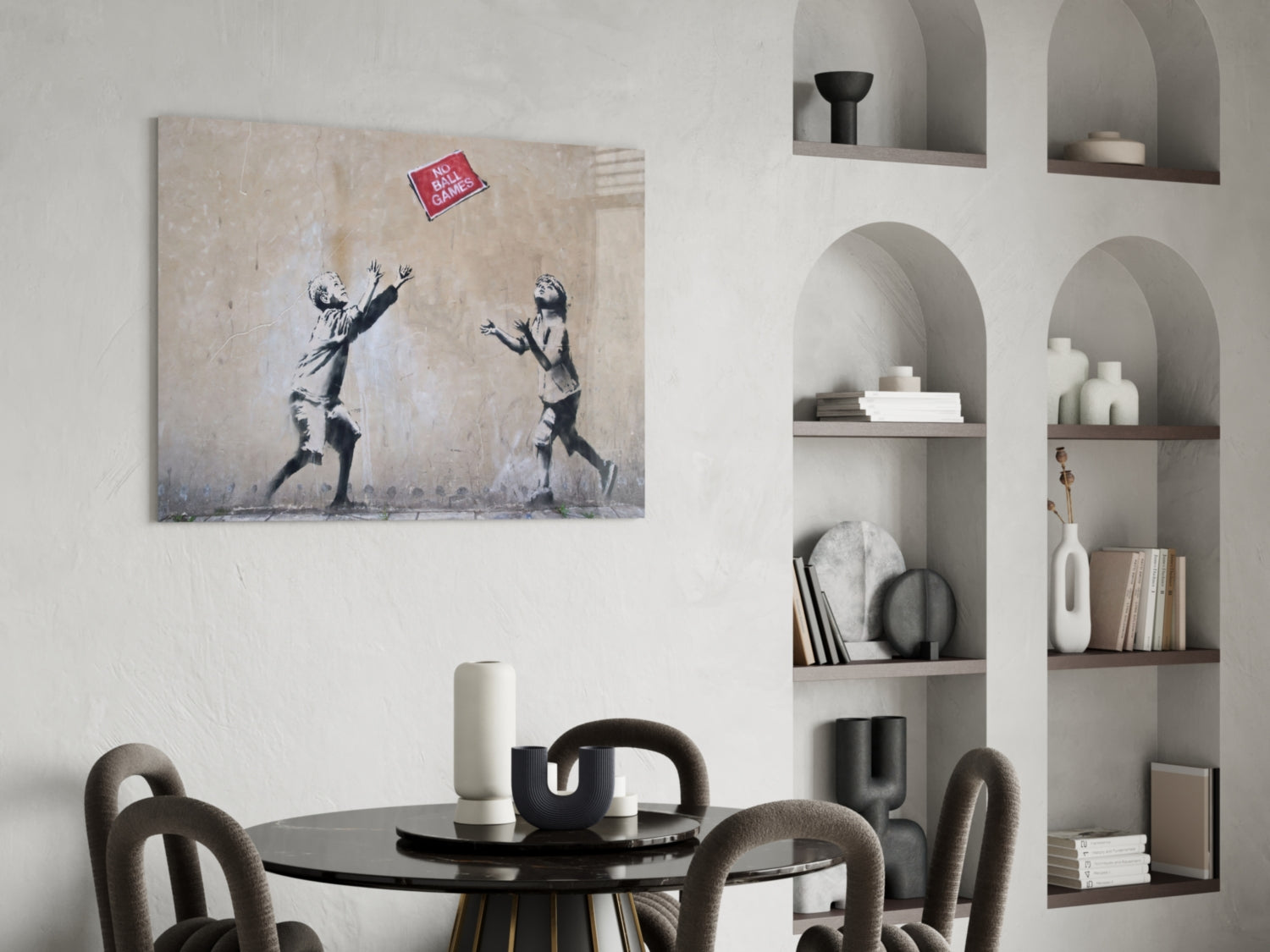 Banksy-style canvas artwork depicting two children reaching for a red "No Ball Games" sign, displayed above a black dining table in a modern interior.