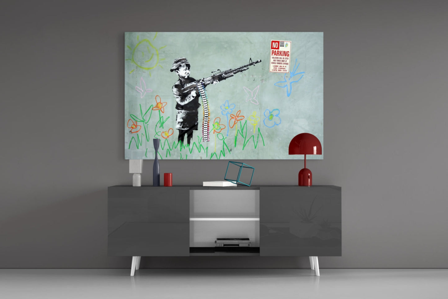 Glass art print mounted above TV stand showing stenciled child figure with gun, colorful flower drawings, and "No Parking" sign on pale background.