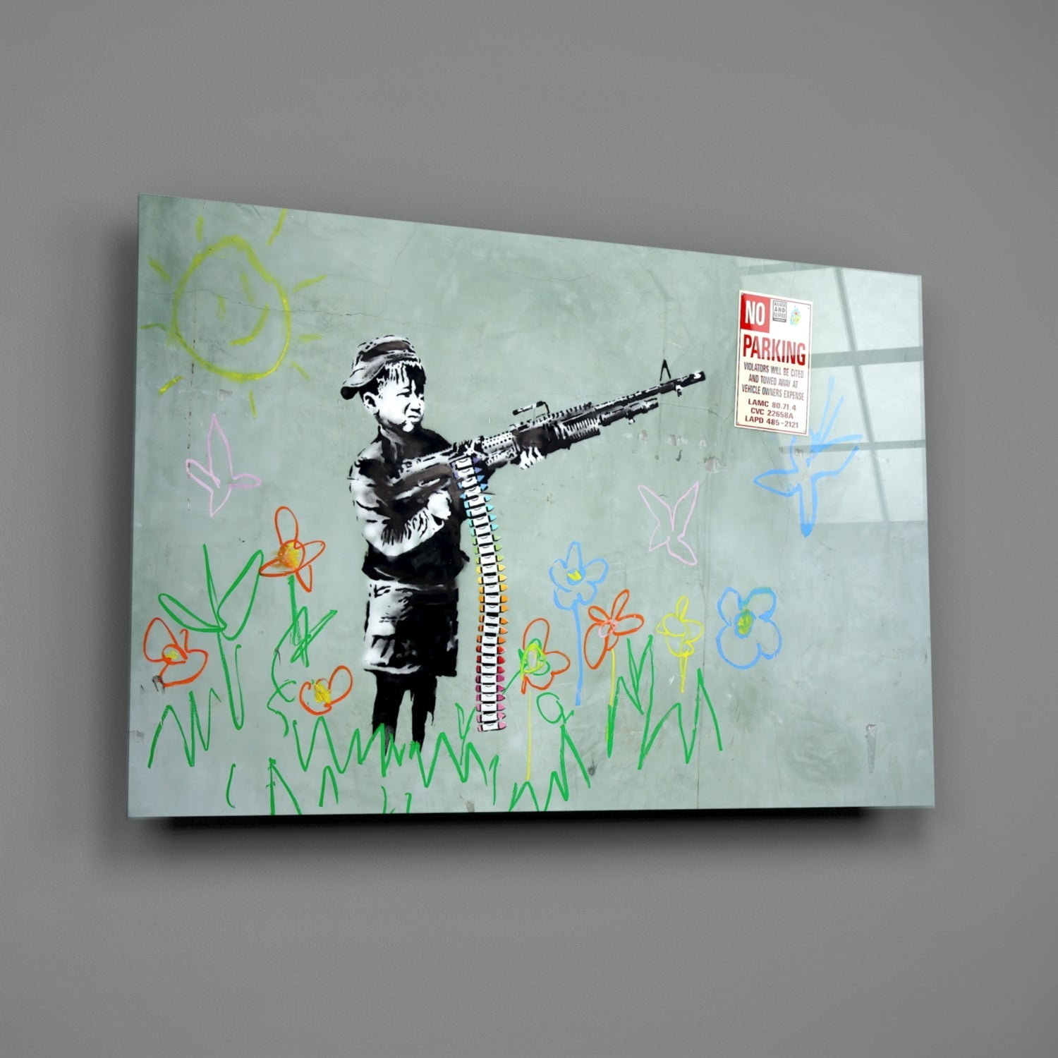 Glass art panel featuring stenciled child holding rifle surrounded by colorful hand-drawn flowers, sun, and "No Parking" sign on pale green background.