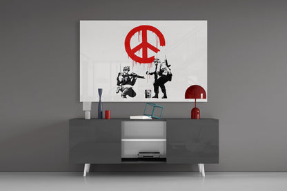 Red and black peace symbol glass art with soldiers displayed above modern gray media console in minimalist interior setting.