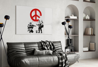 Modern living room featuring black leather sofa with glass wall art displaying red peace symbol and black stenciled figures.