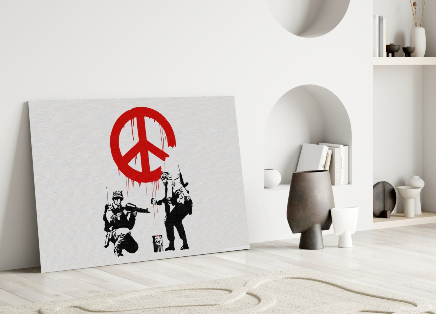 White canvas with red peace symbol and black stenciled soldiers leaning against white wall in minimalist interior setting.