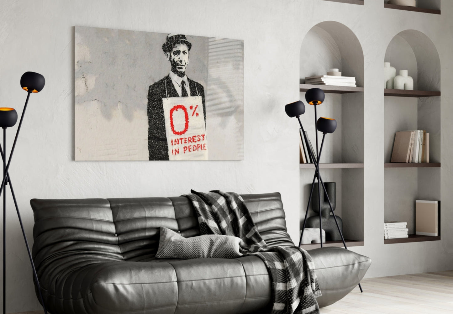 Modern living room with black leather sofa, Banksy-style artwork featuring man holding "0% Interest in People" sign above couch, and arched wall shelving.