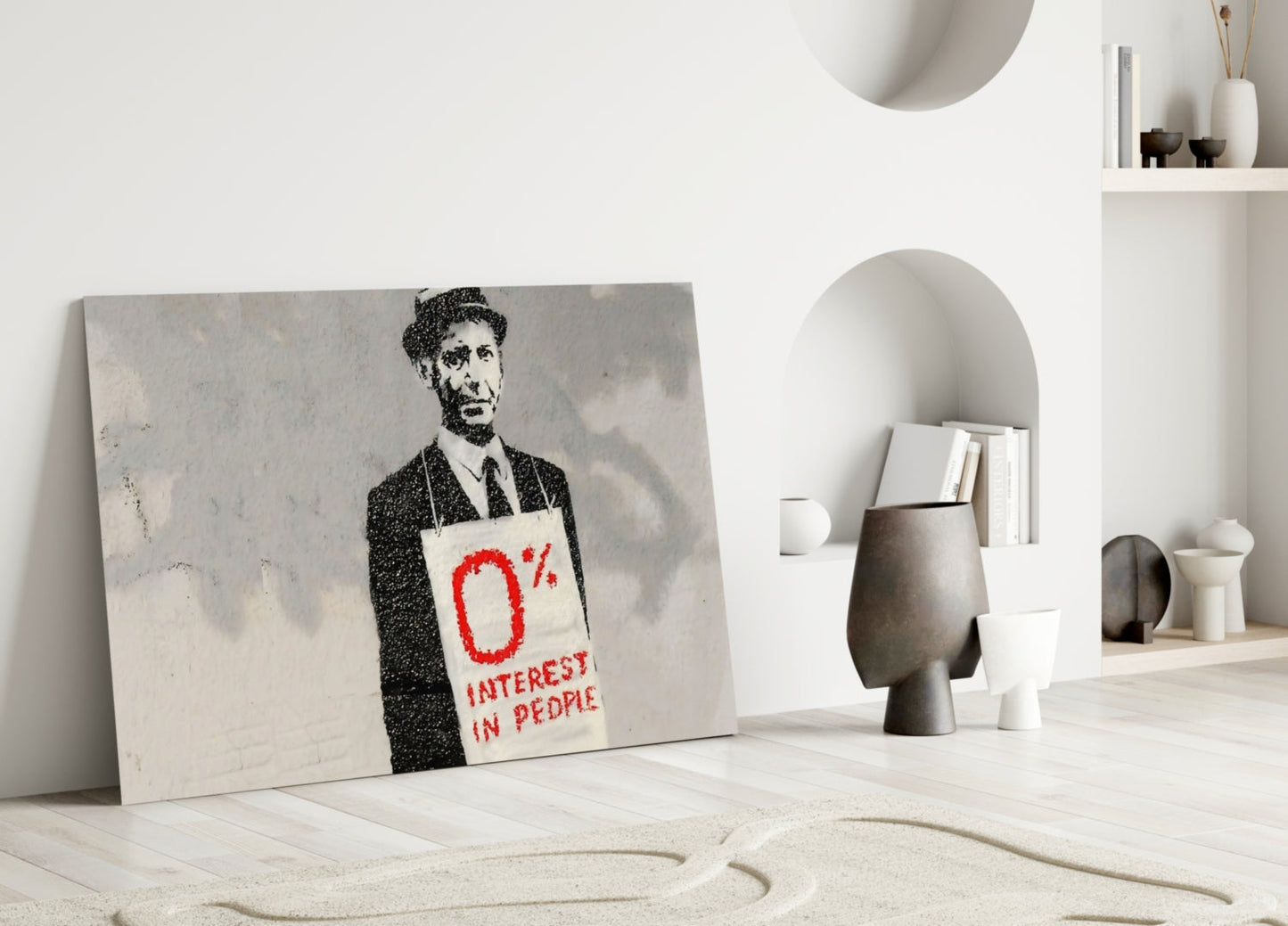 Canvas artwork leaning against white wall displaying stenciled figure in suit holding sign reading "0% INTEREST IN PEOPLE" in red text.