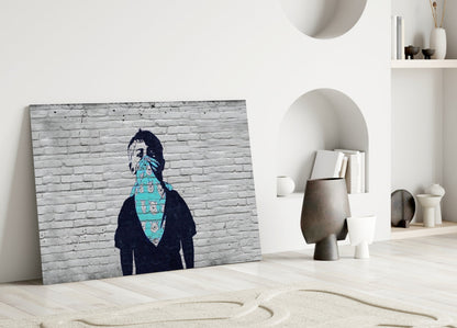 Canvas art leaning against white wall displays figure in dark clothing with turquoise patterned cloth covering face against white brick background.