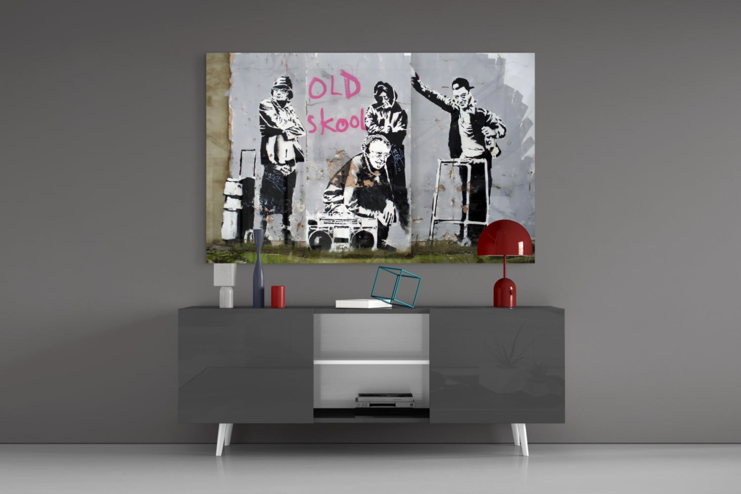 Banksy "Old Skool" stenciled street art print displayed on gray modern TV console with red accents and white legs.