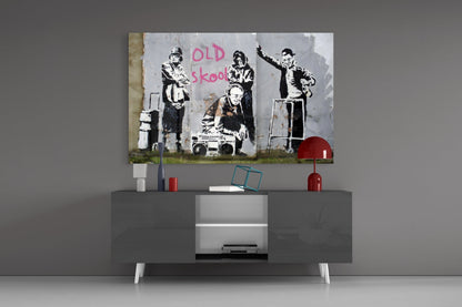 Banksy "Old Skool" stenciled street art print displayed on gray modern TV console with red accents and white legs.