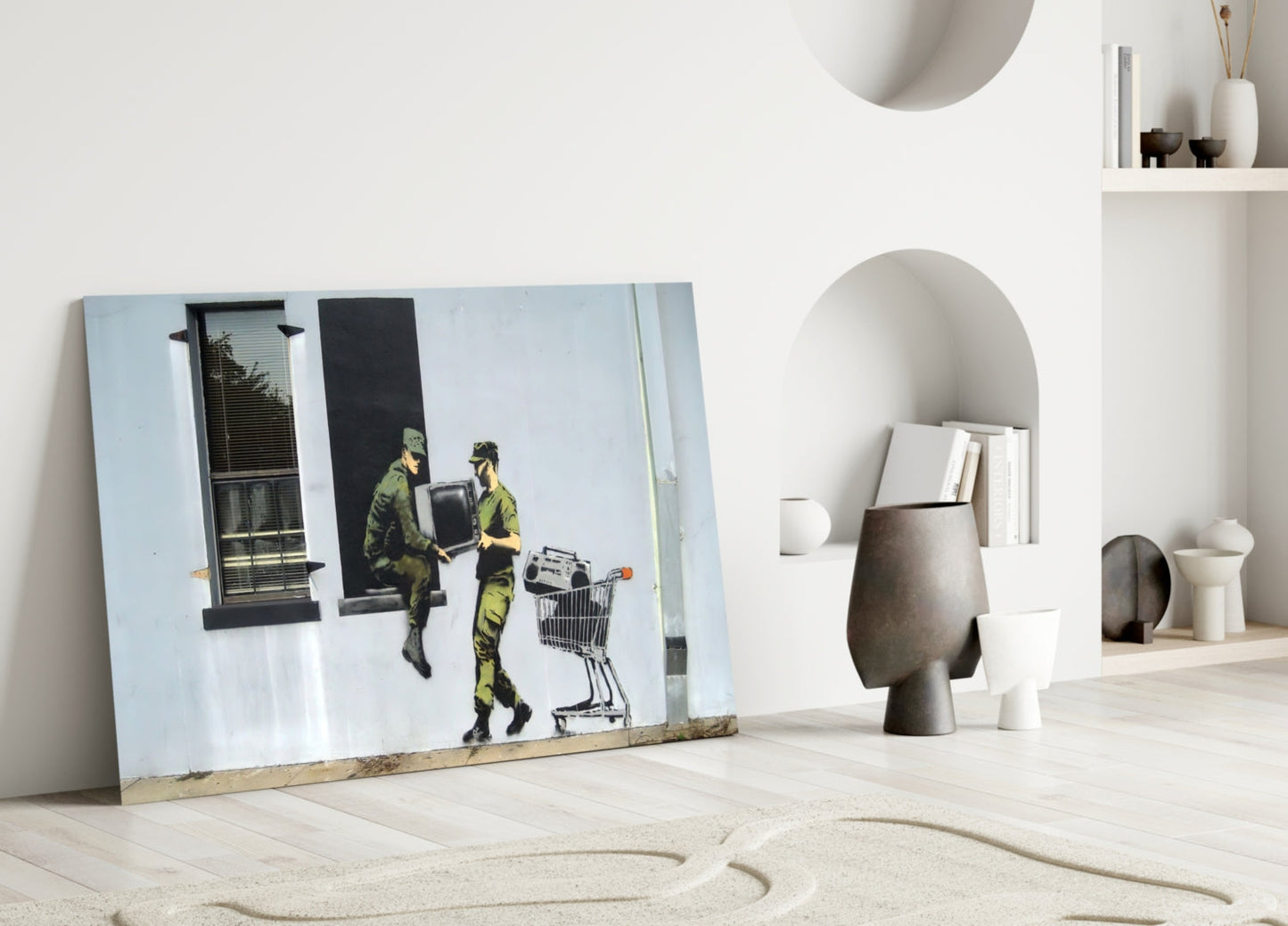 Glass art print leaning against white wall showing two figures in yellow-green carrying television and shopping cart.