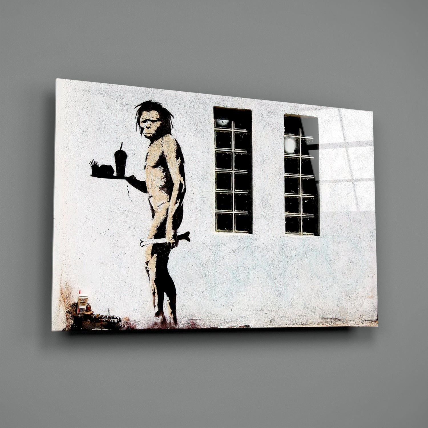 Canvas print of stenciled Neanderthal figure holding burger against white building wall with windows.