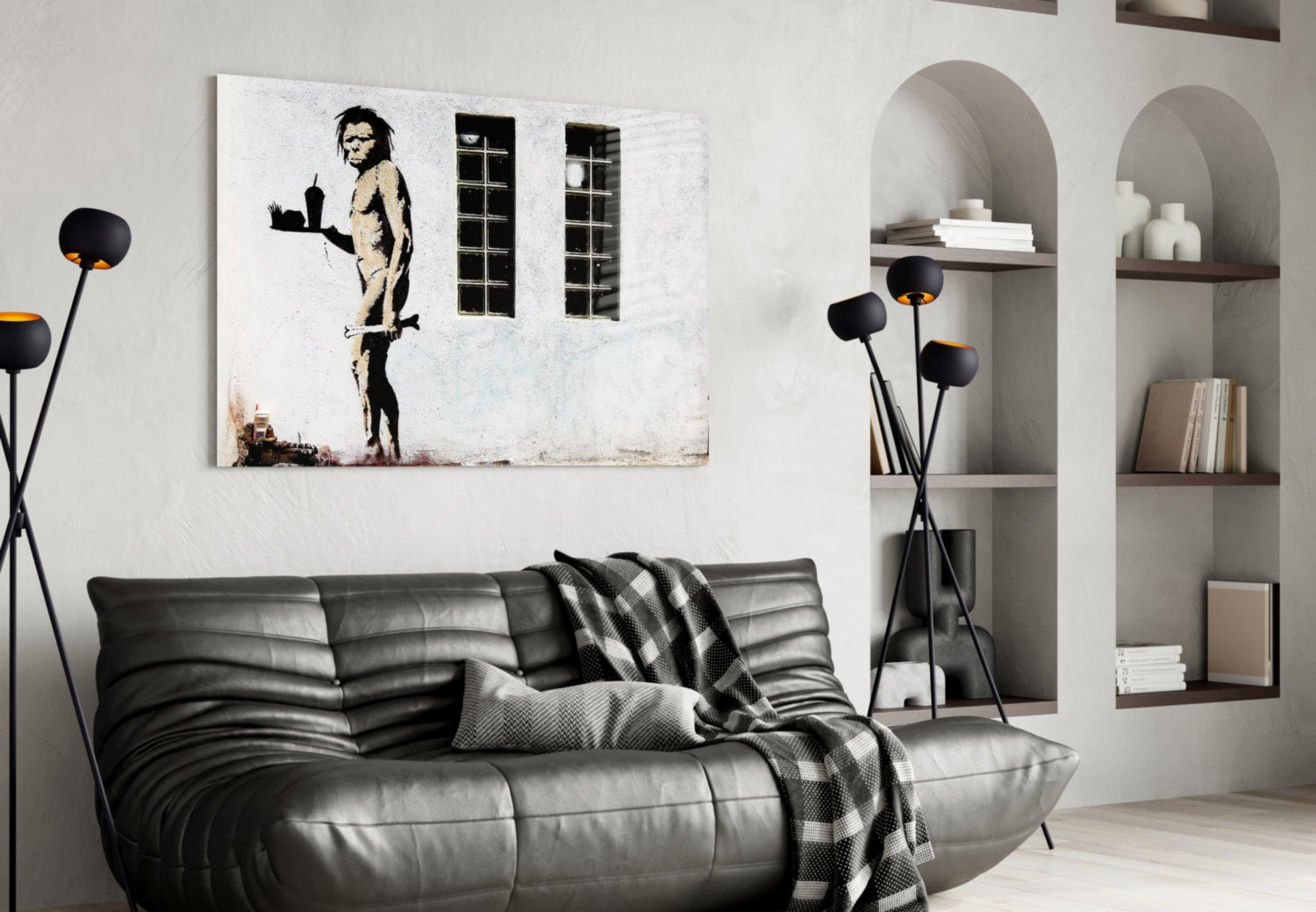 Black and white stencil artwork of a nude figure holding a tray, displayed above a gray leather sofa in a modern living room interior.