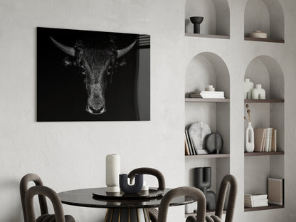 Black and white buffalo portrait glass art displayed above a round black dining table with upholstered chairs.