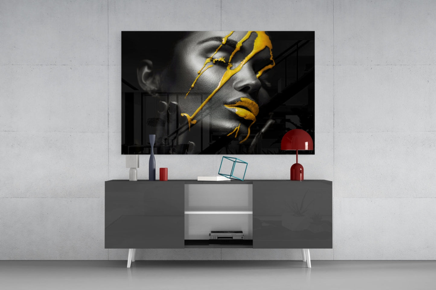 Yellow paint glass art displayed on gray media console in modern living room setting with red lamp and accessories.