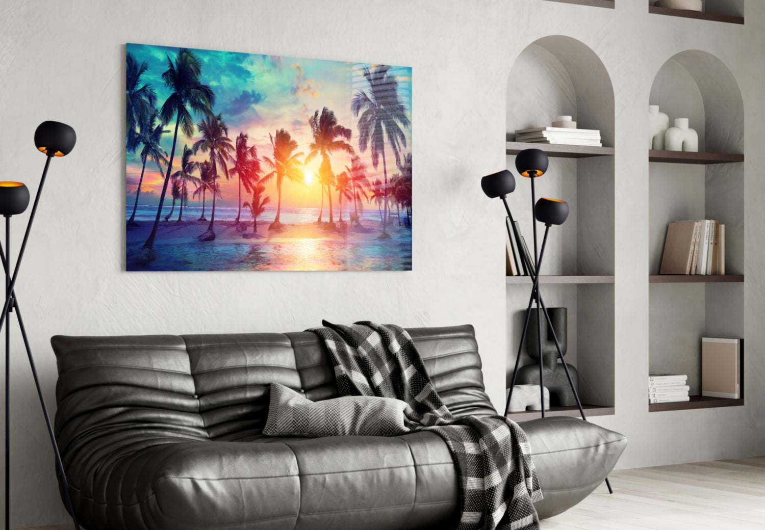 Tropical sunset glass art hanging above black leather sofa in modern living room with arched shelving.
