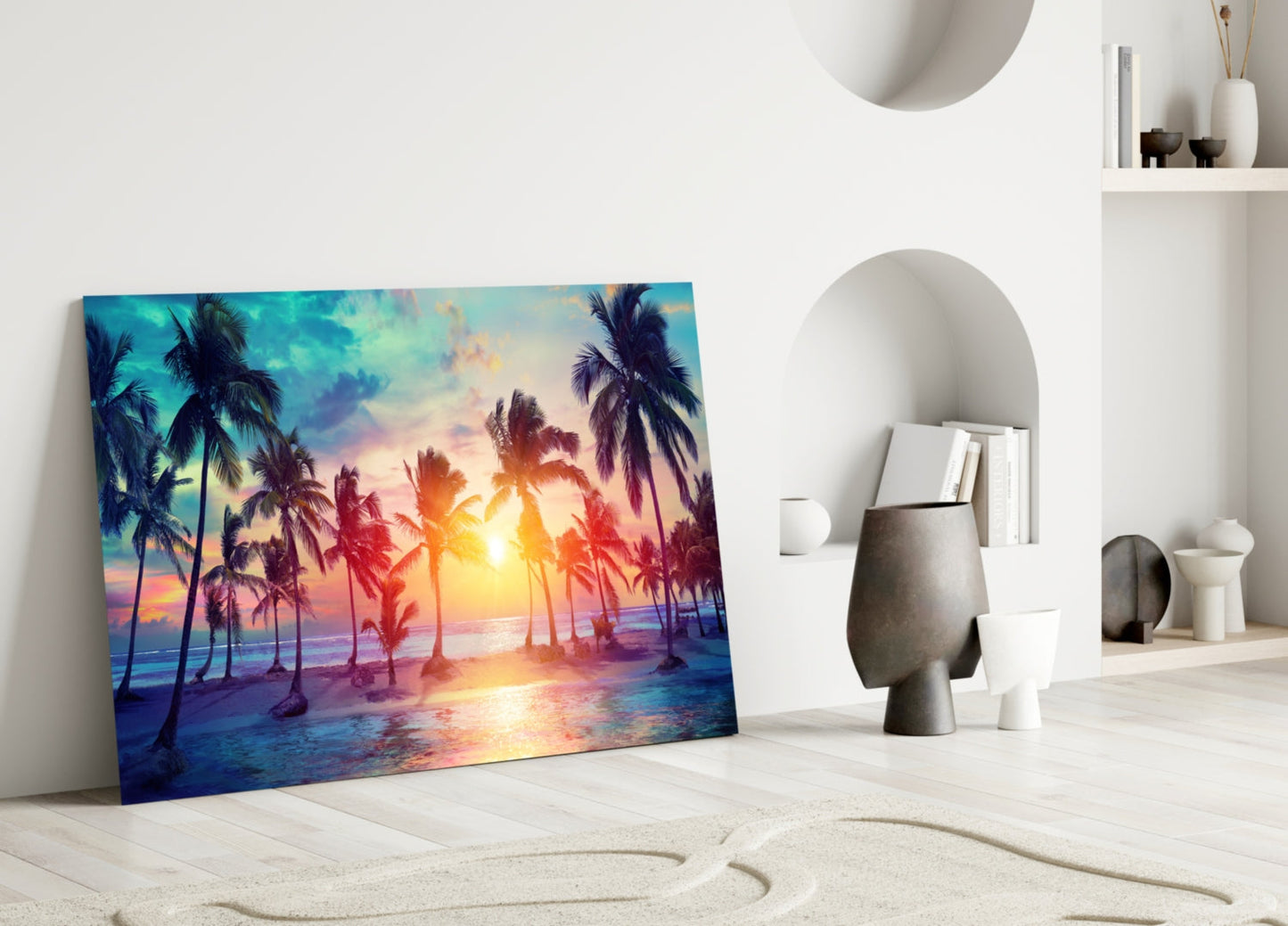 Colorful glass art depicting a vibrant sunset with silhouetted palm trees leaning against a white wall in a minimalist interior setting.