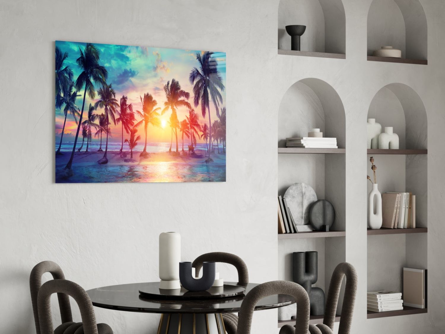 Vibrant tropical sunset artwork with palm trees and golden light displayed on white wall above round black dining table.