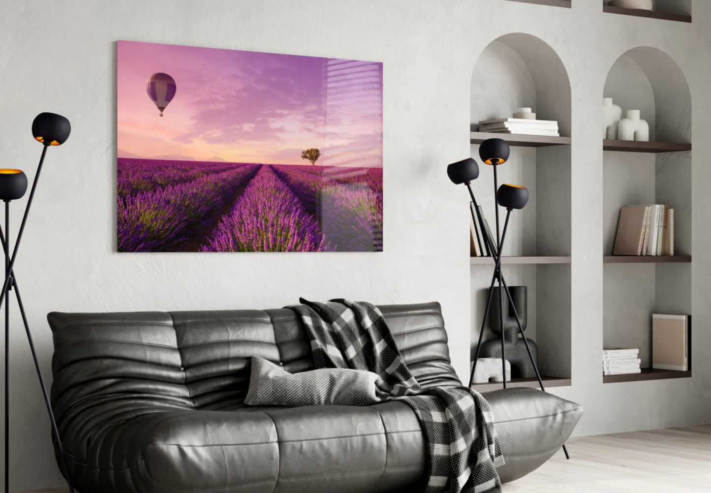 Glass art print of lavender field with hot air balloon at sunset displayed above black leather sofa in modern living room.