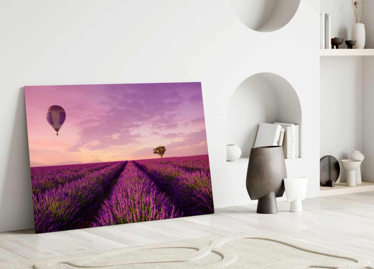 Canvas art leaning against white wall showing purple lavender field with hot air balloon at sunset, displayed in minimalist room setting.