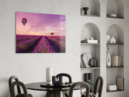 Glass art print of purple lavender field with hot air balloon and solitary tree at sunset, displayed above round black dining table.
