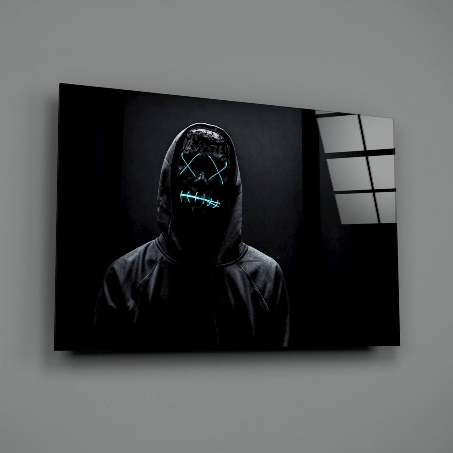 Figure in dark hoodie with neon cyan glowing mask design displayed on framed canvas against gray wall.
