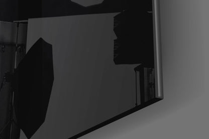 Silhouetted view of a circular sight glass and rectangular panel mounted on a wall, photographed at an angle against gray background.