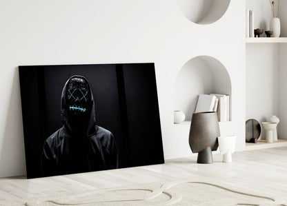 Black canvas with neon cyan glowing mask face leaning against white wall in minimalist room setting.