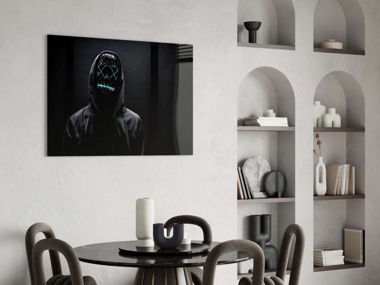 Neon-masked figure with glowing cyan stitched eyes and mouth on black canvas hanging above minimalist dining setup.