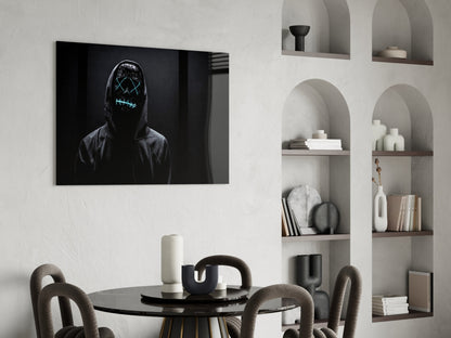 Neon-masked figure with glowing cyan stitched eyes and mouth on black canvas hanging above minimalist dining setup.