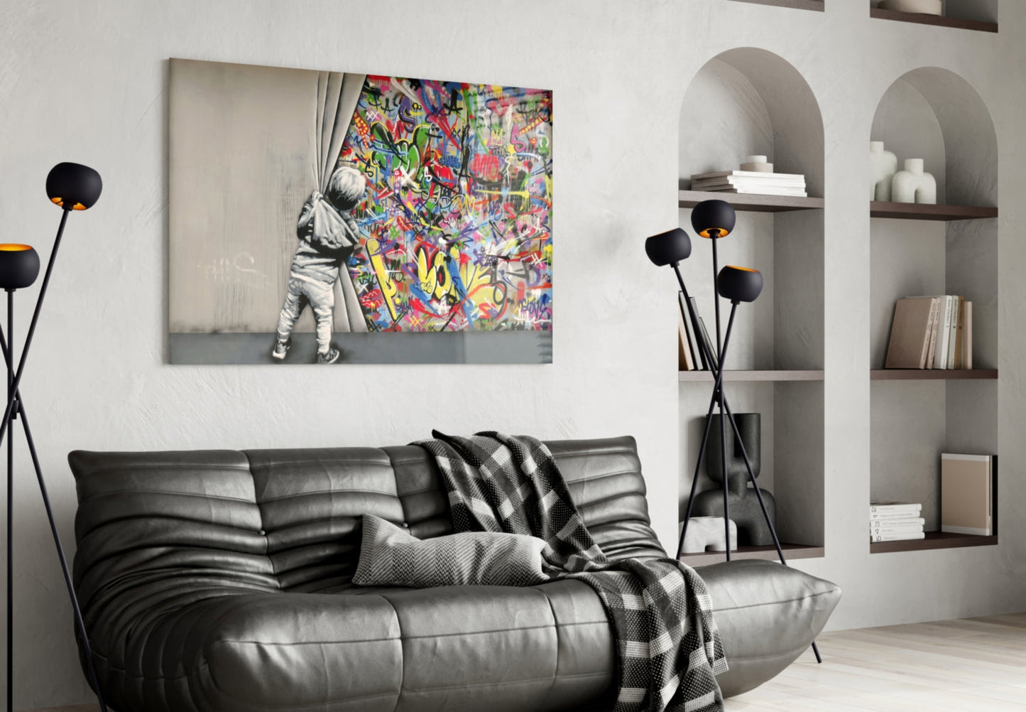 Modern living room with black leather sofa displaying "Behind the Curtain" glass art print featuring child opening colorful graffiti curtain.