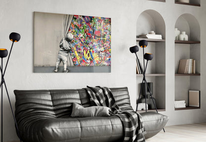 Modern living room with black leather sofa displaying "Behind the Curtain" glass art print featuring child opening colorful graffiti curtain.