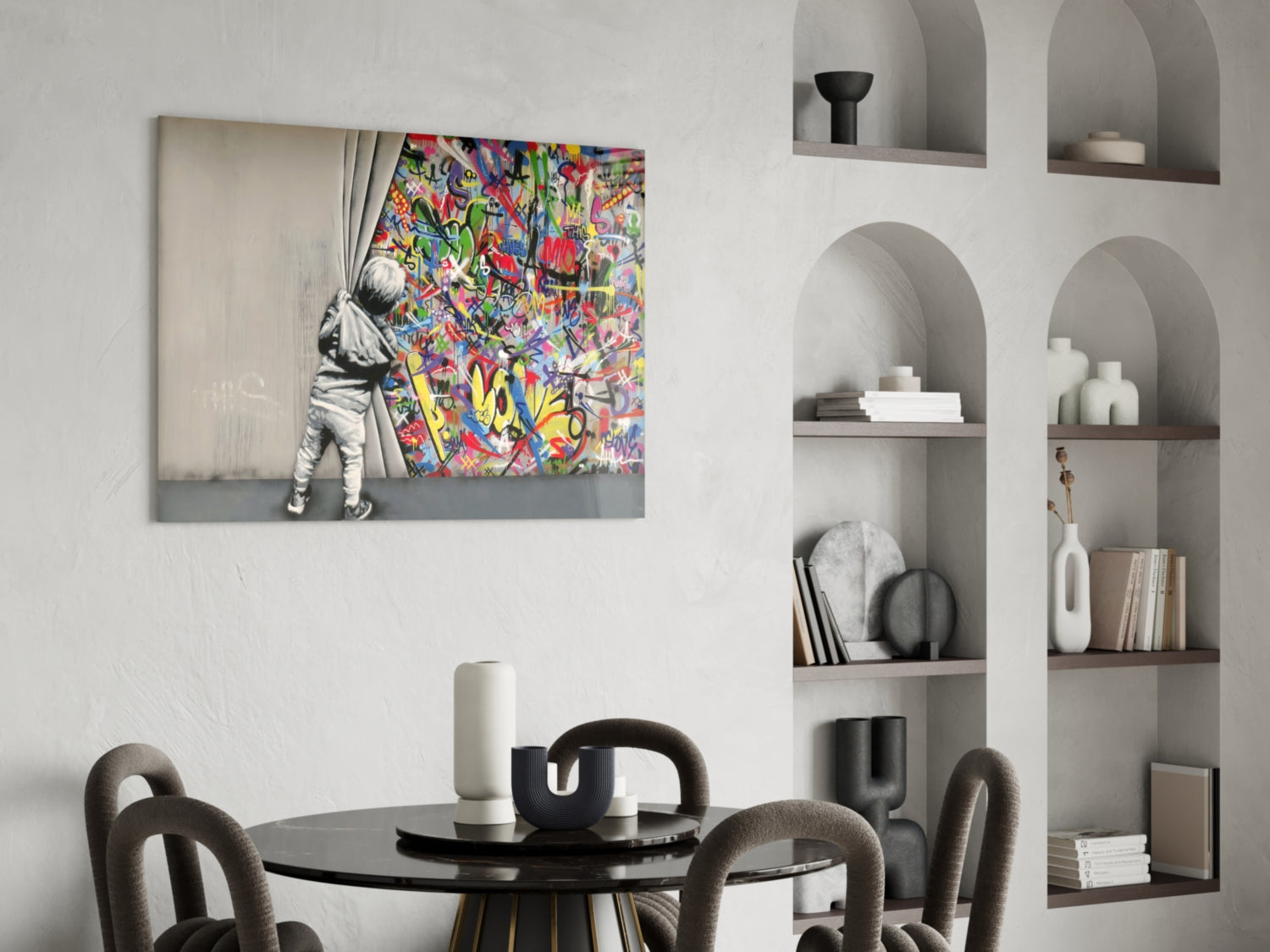 Colorful street art glass panel displayed above a black dining table in a modern interior with built-in shelving.