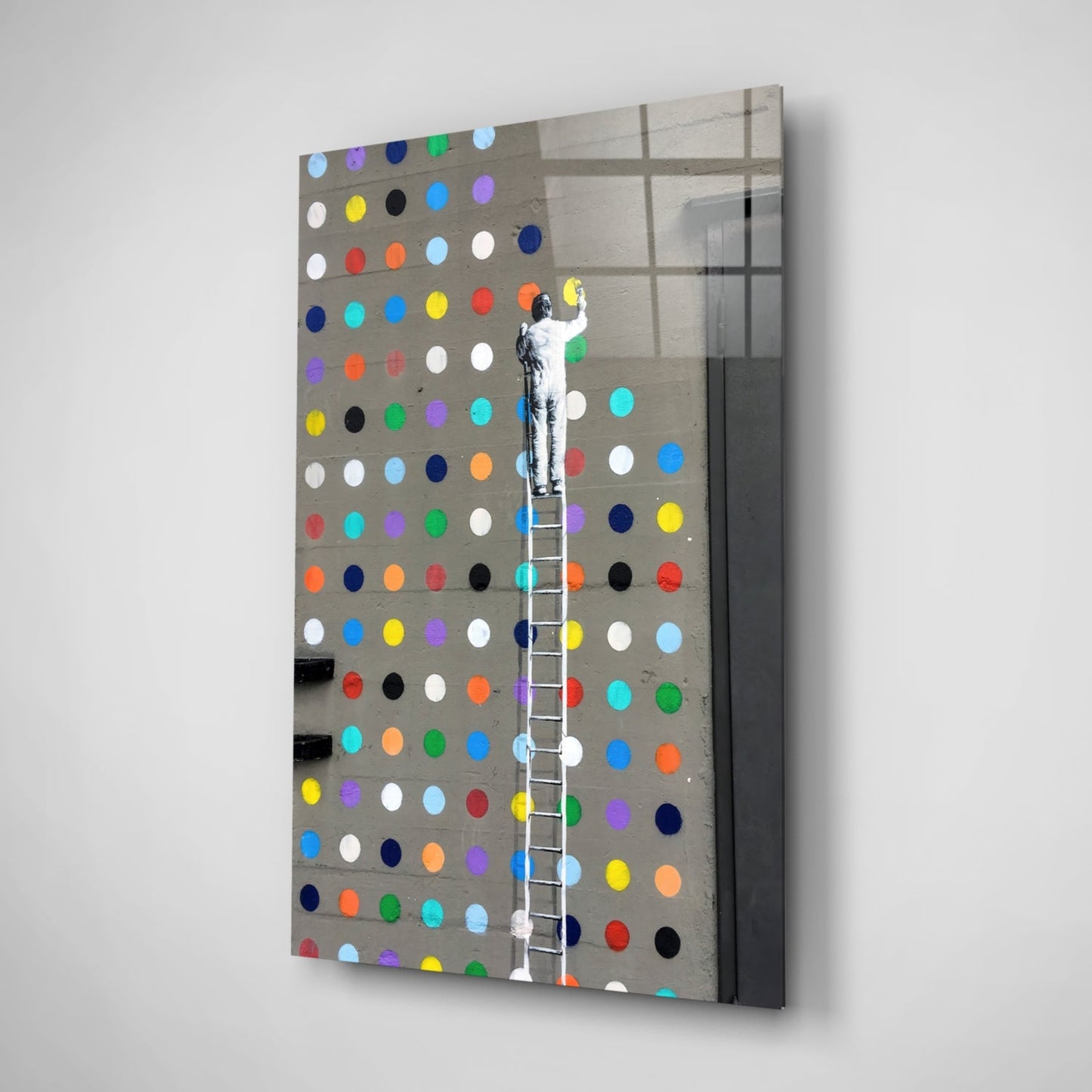 Angled view of glass art panel featuring figure on ladder reaching toward multicolored dots on gray pegboard background.