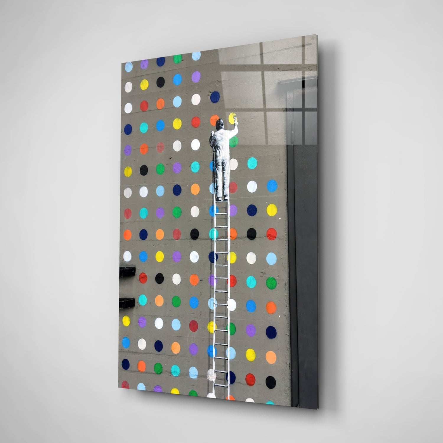 Angled view of glass art panel featuring figure on ladder reaching toward multicolored dots on gray pegboard background.