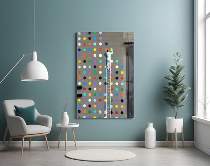 Colorful glass dot artwork displayed on turquoise wall above white chair, showing figure on ladder against multicolored circular dots on gray background.