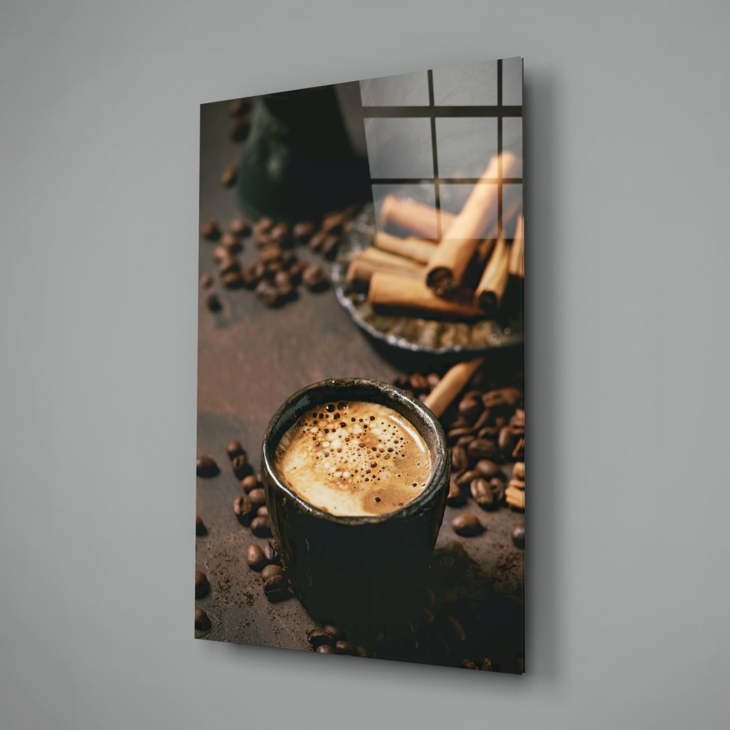 Black mug with latte art surrounded by coffee beans on gray surface, displayed as angled wall-mounted glass panel.