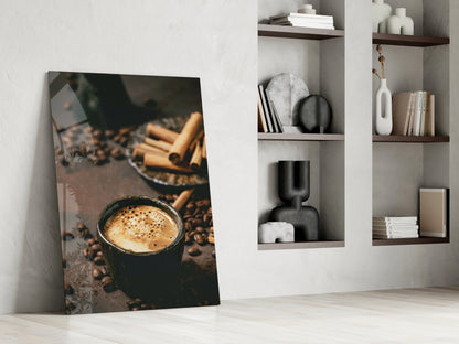 Glass art print of steaming coffee cup with cinnamon sticks and beans, leaning against white wall beside shelving.