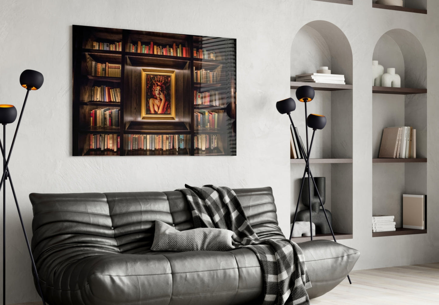 Framed glass art depicting an illuminated library bookshelf with gold-bordered portrait, displayed above black leather sofa in modern living room.