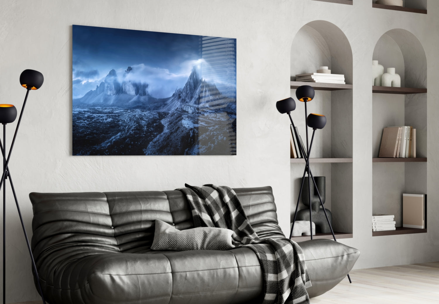 Blue-toned mountain landscape glass art displayed above a dark leather sofa in a modern living room interior.