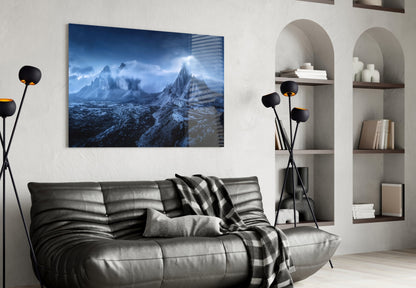 Blue-toned mountain landscape glass art displayed above a dark leather sofa in a modern living room interior.