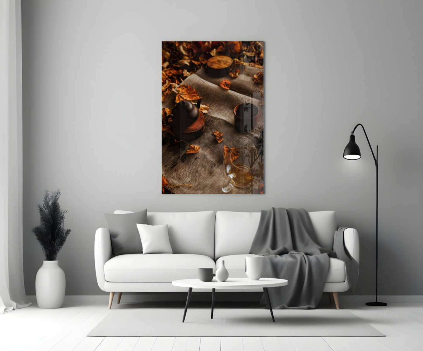 Autumn Picnic Glass Art displayed above a white sofa, showing dark bottles and scattered golden leaves on textured fabric.